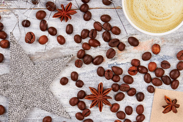 Fototapeta na wymiar Coffee decorations on wooden background. Silver star and coffee beans. Coffe and festive mood.