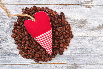 Textile heart on coffee heap. Coffee beans on wooden background. Drink coffee with love.