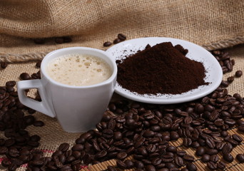 pile instant, powdered coffee, beans,white plate and cup on jute background, texture
