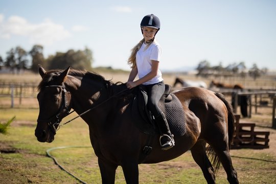 Smiling girl riding a horse in the ranch
