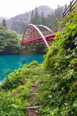 Landscape with view of red arch bridge and vivd blue lake in the forest