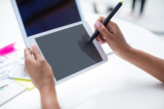 Hands of female graphic designer using graphic tablet at desk