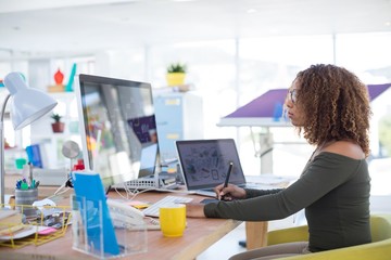 Female graphic designer working at desk - Powered by Adobe