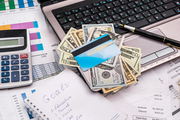 business concept -   laptop, dollar and business report, credit card  at office