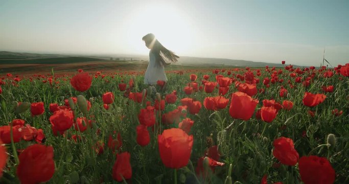 ittle Asian girl in white dress having fun in a field of red poppies in Sunny day, slow motion