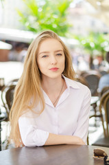 Outdoor summer portrait of young attractive lady in a cafe