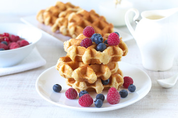 Traditional belgian waffles with fresh berries on a rustic table