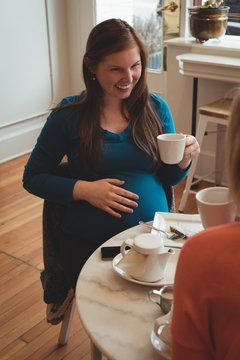 Pregnant woman having coffee in restaurant
