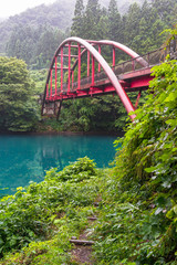 Lake shore with path and red suspension bridge