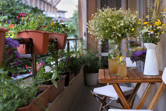 Balcony seating for relaxation. Table with homemade lemonade, bunches of herbs and wild flowers.