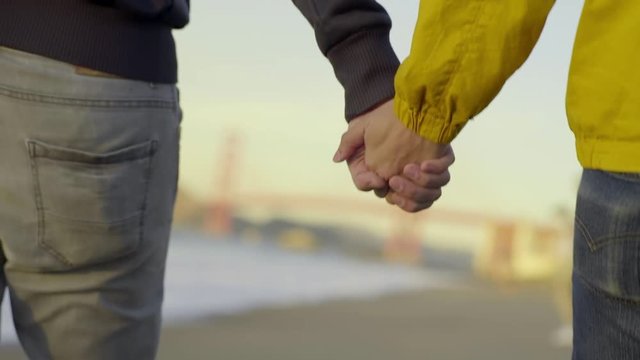 Gay Couple Hold Hands And Walk Down Beach Toward Golden Gate Bridge (Slow Motion)