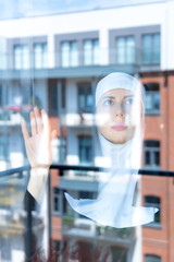 Young sad nun near window