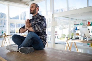 Male executive performing yoga on a table