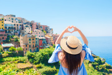 Happy girl making with hands heart shape on the old coastal village in Cinque Terre National Park....