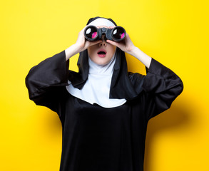 Young surprised nun with binoculars