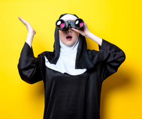 Young surprised nun with binoculars