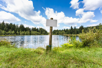 white empty sign in front of blue lake with buoys