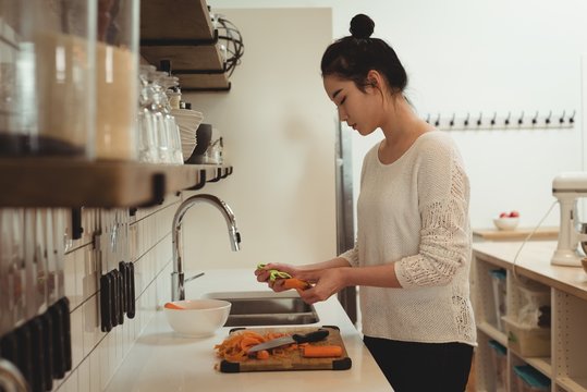 Woman peeling vegetables in kitchen sink