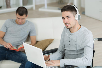 Obraz premium Disabled adolescent looking at laptop and wearing headphones