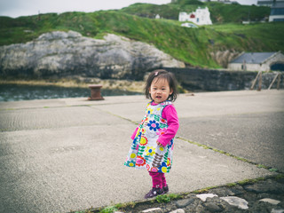 Fototapeta premium baby girl walking in small harbor,Northern Ireland