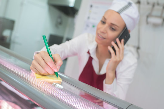 female butcher on the phone behind counter