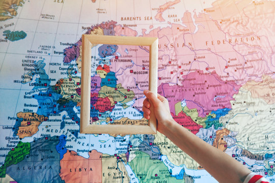 hand holding empty wooden frame on Europe map background
