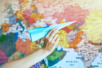 Fototapeta na wymiar hand with paper origami airplane on world map background