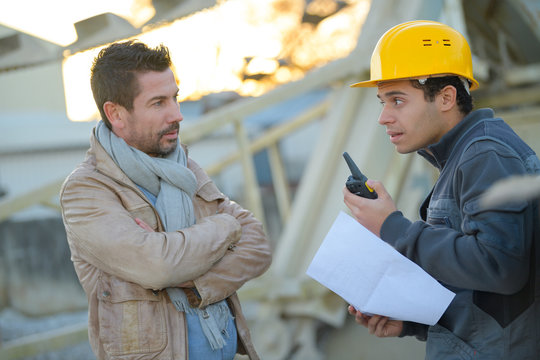 entrepreneur and builder on building site using walkie talkie