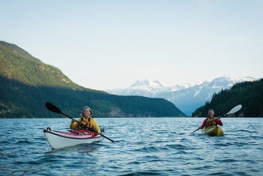 Couple in kayak over lake against sky