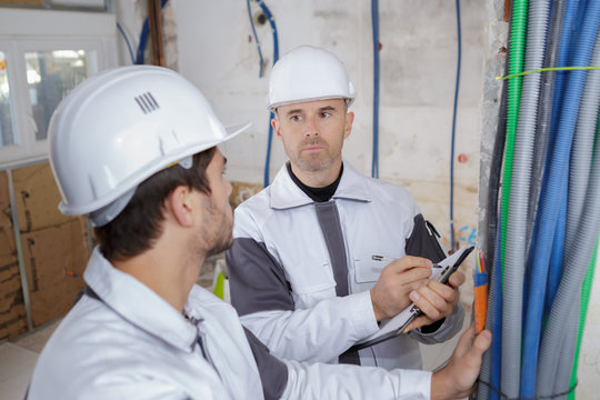 builders discussing about water pipes in boiler room