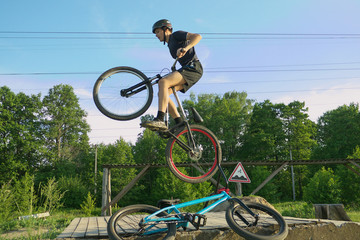 Fototapeta na wymiar Young man jumping and riding on a BMX bicycle downhill