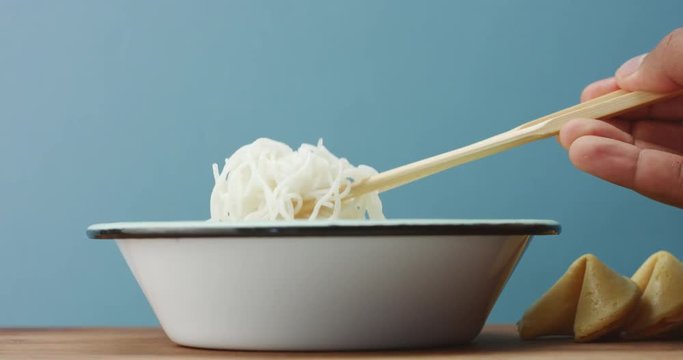man's hand with an asian sticks does not let an another person try rice noodles.