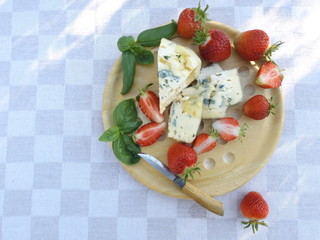 Cheeseboard. Cheese with blue mold, strawberry and honey on a round wooden board.
