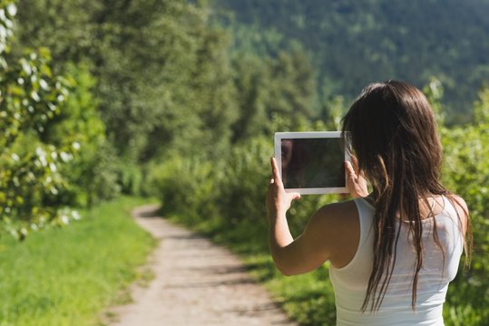 Woman using digital tablet in forest path