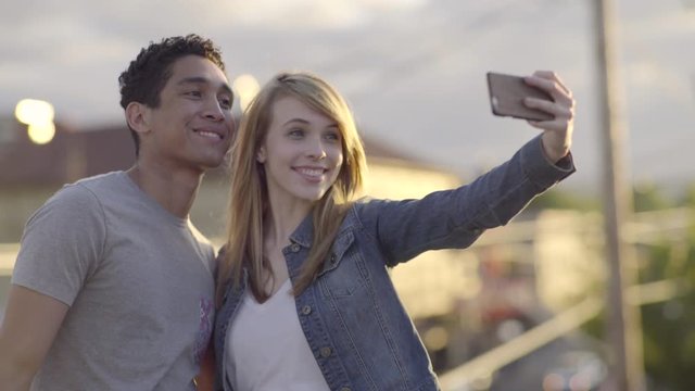 Cute Couple Take Silly Selfies On A Rooftop At Sunset In The City 