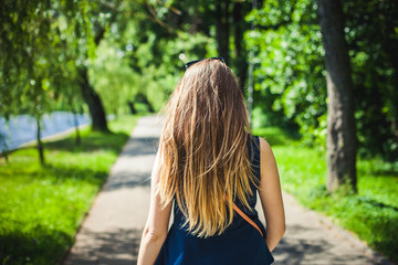 Young student girl walking in a park by the lake.