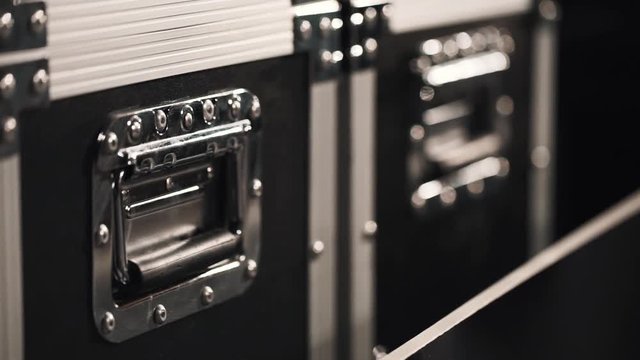 Handles of black metal boxes for scenery equipment in dark storage room, close up isolated tracking shot