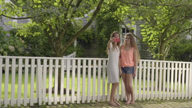 Teen Girls Take Photos Together In Front Of Yard In Neighborhood