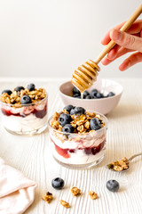 Cooking breakfast with granola and berries on white kitchen back