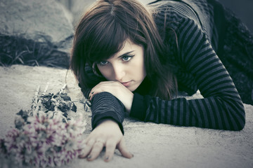Sad young woman with a flowers lying on tombstone