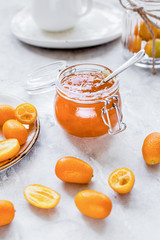 kumquat on plate and jam in jar at gray background
