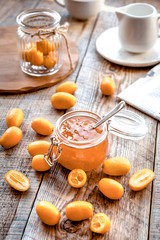 kumquat on plate and jam in jar at wooden table