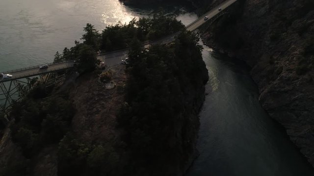 Aerial of Cars on Weekend Vacation Traveling Across High Ocean Bridge Between Islands with Golden Hour Lens Flare