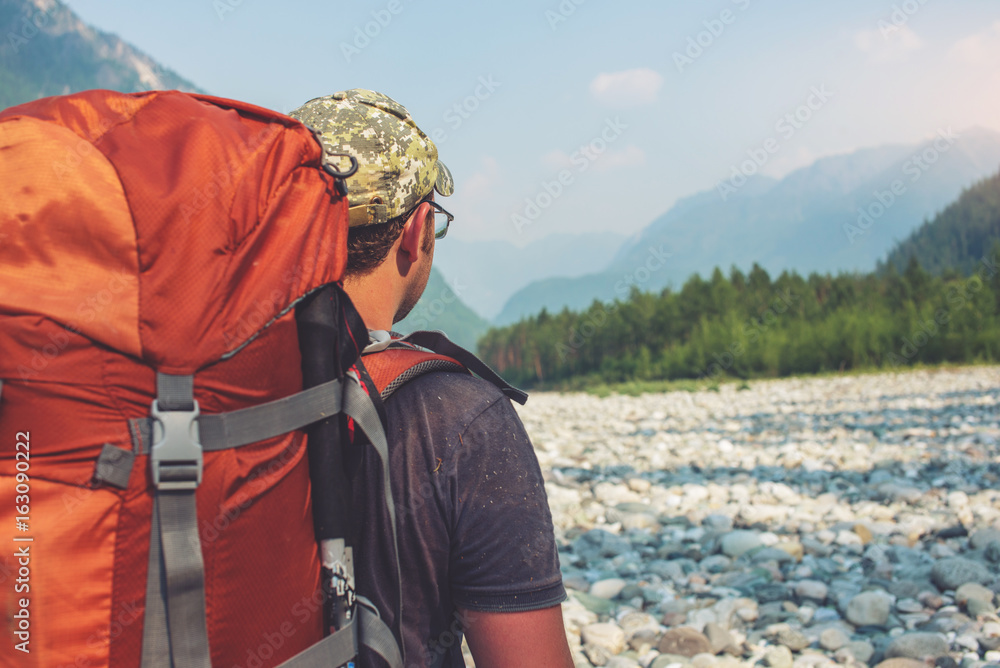 Wall mural healthy active man with backpack hiking in beautiful mountain forest in the summer in the sun