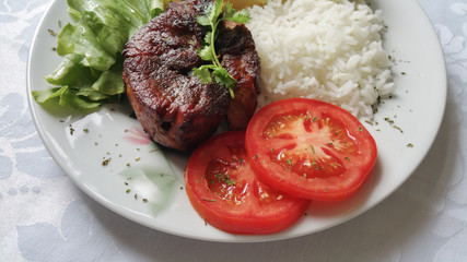Lunch plate with roast pork, rice, tomato and lettuce