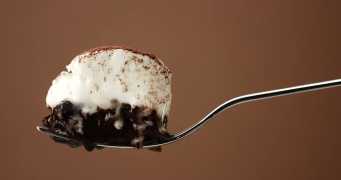piece of chocolate cake on a fork with a white cream and a liquid topping