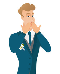 Young shoked caucasian groom covering his mouth.
