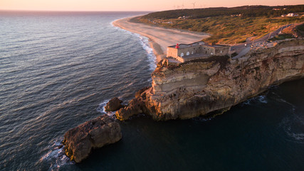 Aerial view of ocean, north Beach and Nazare lighthouse at sunset, Portugal