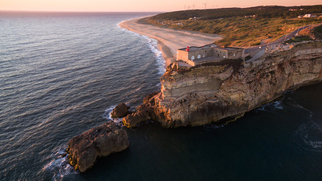 Aerial view of ocean, north Beach and Nazare lighthouse at sunset, Portugal