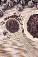 Dust and acai fruit on the wooden spoon (Euterpe oleracea)